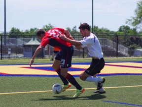 Kingston FC's Guillaume Surot tries to control the ball with a SC Waterloo player all over his back during Canadian Soccer League action at Queen's University's West Campus field on Sunday. (Chloe Sobel/For The Whig-Standard)