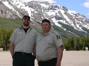 Wildfire ranger Jason McAleenan (l) and wildfire technologist Stefan Best (r) stand in the parking lot at Castle Mountain. They are part of the team that will burn out a 60 hectare strand of forest that is visible just behind Best’s left shoulder. John Stoesser photo/QMI Agency.