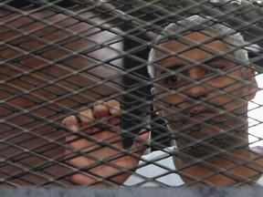 Al Jazeera journalist Mohammed Fahmy stands behind bars at a court in Cairo May 15, 2014. (REUTERS/Stringer)