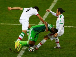 Iran's Alireza Jahanbakhsh (left) and Andranik Teymourian (right) fight for the ball with Nigeria's Emmanuel Emenike during their World Cup match at the Baixada arena in Curitiba, Brazil on Monday, June 16, 2014. (Amr Abdallah Dalsh/Reuters)
