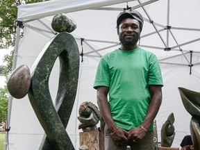 Chaka Chikodzi stands next to one of his handmade stone sculpture)s at Artfest Kingston at City Park last year. (Whig-Standard file photo)