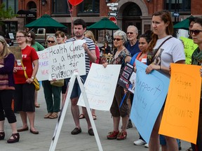 Supporters in Springer Market Square hold up signs to put an end to refugee health-care cuts during the third National Day of Action on Monday. (Alex Pickering/For The Whig-Standard)