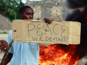 A resident holds a placard as he participates in a protest against the recent attack by unidentified gunmen in the coastal Kenyan town of Mpeketoni, June 17, 2014. Kenya's President Uhuru Kenyatta said on Tuesday that two days of attacks on the coast in which about 65 people were killed were planned by "local political networks", dismissing claims by Somalia's al Shabaab Islamist group that it was behind the assaults. REUTERS/Joseph Okanga