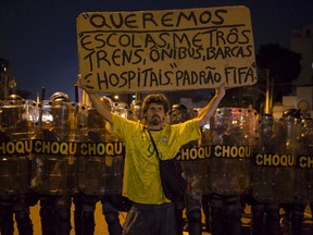 A protester stands in front of riot police during a demonstration against the public spending for the 2014 World Cup, in Rio de Janeiro June 15, 2014. The sign reads,