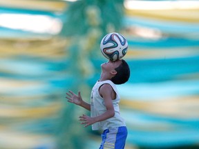 A boy play soccer with a Brazuca ball on a street decorated with references to the World Cup in Brasilia, Brazil on June 11, 2014. (Ueslei Marcelino/Reuters)