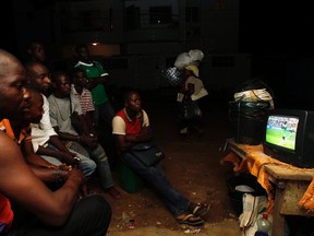 People watch the 2014 World Cup Group F soccer match between Nigeria and Iran on a street in Abidjan on June 16, 2014. (REUTERS/Luc Gnago)