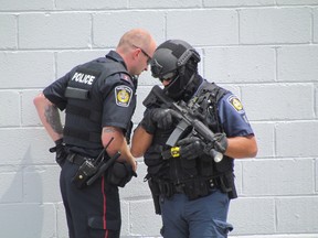 Police officers stand next to a commercial building at the corner of Brock and Lochiel streets in Sarnia during a nine-hour standoff Tuesday. (PAUL MORDEN, The Sarnia Observer)