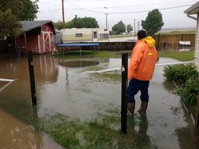 A man looks over a flooded backyard in Claresholm, Alta. on June 18, 2014. Darren Makowichuk/Calgary Sun