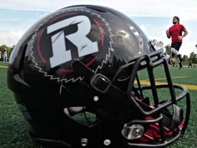 Ottawa RedBlacks helmet sits along the sidelines during practice. RedBlack Travis Brown runs in the background.  Tony Caldwell/Ottawa Sun/QMI Agency