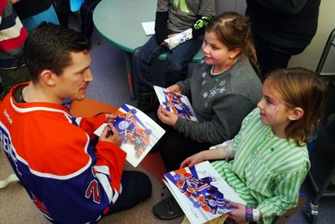 Andrew Ference signs som autographs for Jae Fehr (r) and Destiny Desfosses (c) during a visit to the Stollery Hospital.  The Edmonton Oilers visits several hospital in Edmonton, AB., on Wednesday, Nov 20, 2013.  Perry Mah/Edmonton Sun/ QMI Agency