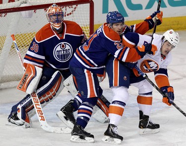 The Edmonton Oilers' Andrew Ference (21) battles the New York Islanders' Anders Lee (27) in front of Oilers' goalie Ben Scrivens (30) during second period NHL action at Rexall Place in Edmonton Alta., on Thursday March 6,  2014. David Bloom/Edmonton Sun/QMI Agency
