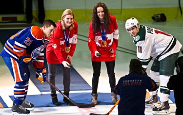 Canadian Olympic women's hockey team members Hayley Wickenheiser, centre left, and Shannon Szabados, centre right, take part in a puck drop with Edmonton's Andrew Ference (21) and Minnesota's Zach Parise (11) during the first period of the Edmonton Oilers' NHL hockey game against the Minnesota Wild at Rexall Place in Edmonton, Alta., on Thursday, Feb. 27, 2014. Codie McLachlan/Edmonton Sun/QMI Agency