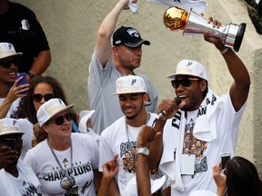 San Antonio Spurs forward Kawhi Leonard (right) hoists the trophy for the fans during the NBA championship parade at San Antonio River Walk on Jun 18, 2014 in San Antonio, TX, USA. (Soobum Im/USA TODAY Sports)