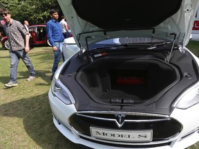 Visitors look at a Tesla Model S electric car at the Motorexpo in Canary Wharf, London, June 13, 2014. Instead of a Ferrari Testarossa, the next