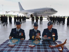 Incoming commander of 437 Transport Squadron at 8 Wing/CFB Trenton, Ont., Lt. Col. Kevin Hendrik Tromp, left, signs official documents along with 8 Wing commander Col. David Lowthian, centre, and outgoing commander of 437, Lt. Col. Ryan Eyre, during a change of command ceremony held in Hangar 1 at the air base Friday, June 20, 2014. - Jerome Lessard/The Intelligencer/QMI Agency
