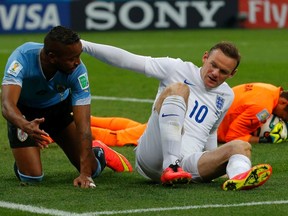 England's Wayne Rooney (middle) hits the ground next to Uruguay's Alvaro Pereira after missing a chance to score during the World Cup match at the Corinthians arena in Sao Paulo June 19, 2014. (REUTERS/Laszlo Balogh)