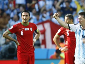 Argentina's Lionel Messi (right) celebrates after scoring  while Iran's Javad Nekounam (left) and Amir-Hossein Sadeghi look on during their World Cup match at the Mineirao stadium in Belo Horizonte June 21, 2014. (REUTERS/Kai Pfaffenbach)