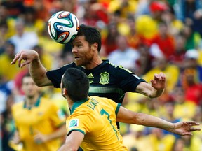Spain's Xabi Alonso jumps for the ball with Australia's Matthew Leckie during their World Cup Group B match at Baixada Arena in Curitiba, Brazil, June 23, 2014. (STEFANO RELLANDINI/Reuters)