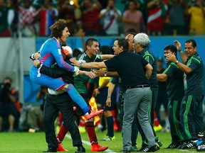 Mexico's coach Miguel Herrera (2nd L) celebrates with goalkeeper Guillermo Ochoa the second goal of their team during their 2014 World Cup Group A soccer match against Croatia at the Pernambuco arena in Recife June 23, 2014. (REUTERS/Eddie Keogh)