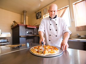 Roberto Vergalito slices a beer infused Buffalo chicken pizza that was one of the novelty pizzas served during Roberto's Pizza Passion's grand opening on Saturday, June 21, 2014. The event included specialty pizzas, a pizza cake from Chiveller Cakes in Niagara Falls and a pizza dough tossing lesson for the kids. 
Julie Jocsak/ St. Catharines Standard/ QMI Agency
