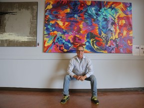 Steve Tracy sits beneath his painting, Big Bang Primarily, part of Corporate Colours, an exhibition on at Art With Panache. (Richard Gilmore/Special to QMI Agency)