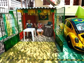 A couple sit under a roof outside their home ahead of the World Cup 2014 match between Brazil and Mexico, in Manaus June 17, 2014. (REUTERS/Yves Herman)