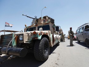 Members of the Iraqi security forces take up positions along a road during an intensive security deployment west of Baghdad, June 24, 2014. (REUTERS/Ahmed Saad)