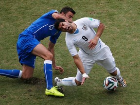 Uruguay's Luis Suarez fights for the ball with Italy's Andrea Barzagli during their 2014 World Cup Group D soccer match at the Dunas arena in Natal June 24, 2014. (REUTERS/Carlos Barria)