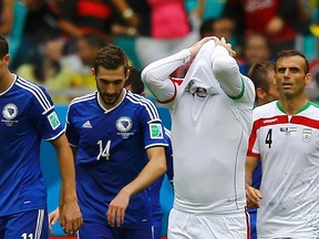 Iran's Andranik Teymourian (secon right) and Jalal Hosseini (right) react as Bosnia's Edin Dzeko (left) and Tino Sven Susic celebrate their team's second goal during their World Cup match at the Fonte Nova arena in Salvador, Brazil on Wednesday, June 25, 2014. (Ivan Alvarado/Reuters)