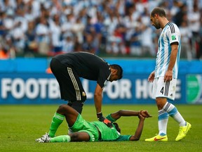 Nigeria's Michel Babatunde holds his wrist in pain after being hit with a shot from teammate Ogenyi Onazi, as Argentina's Pablo Zabaleta watches, during their World Cup match at the Beira Rio stadium in Porto Alegre, Brazil on Wednesday, June 25, 2014. (Darren Staples/Reuters)
