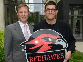 Principal Kim Hackman (L) and student Mihnea Nitu, 17yrs, from Western Canada High School on 17th ave SW  in downtown Calgary Alta. show the new school team logo after it was changed from the Redmen to the Redhawks on Thursday June 26, 2014. Stuart Dryden/Calgary Sun/QMI Agency