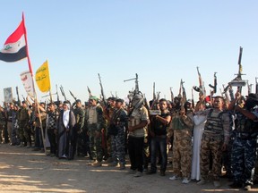 Shi'ite volunteers, who have joined the Iraqi army to fight against the predominantly Sunni militants from the radical Islamic State of Iraq and the Levant (ISIL), wave flags and hold weapons during a parade on a street in Kanaan, Diyala province, June 26, 2014. (REUTERS/Stringer)