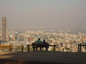 A man sits with his son while enjoying the view of the Andes Mountains Range at the San Cristobal Hill in Santiago de Chile February 8, 2012. REUTERS/Minh Nguyen/Files