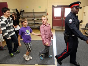 FILE: EPS Cst. Robert Butchike and thirty-eight St. James Catholic School Grade 5 and 6 students march into the gym for the school's first Drug Abuse Resistance Education (DARE) graduation in Edmonton, Alta., Friday June 21, 2013. David Bloom/Edmonton Sun