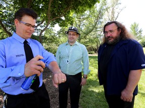 Edmonton Animal Care and Pest Management's James Wike sprays on some bug spray as Dr. Chris Sikora (c), and Mike Jenkins, biological science technician watch on during a news conference in Edmonton, Alta., on Friday, June 27, 2014.  Perry Mah/Edmonton Sun/QMI Agency