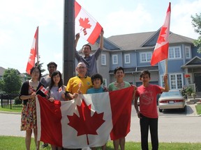 Edison Ramos along with family and friends are hanging Canadian flags on light poles in their Mississauga neighbourhood. (Angela Hennessy/Toronto Sun)