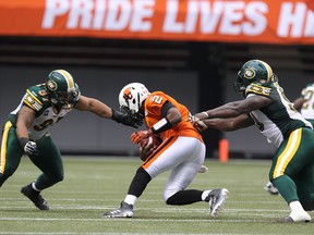 Edmonton Eskimos' Eddie Steele (left) Almondo Sewell (right) tackles BC Lions’ quarterback Kevin Glenn during the first half of CFL game at BC Place in Vancouver, B.C. on Saturday June 28, 2014. Carmine Marinelli/QMI Agency