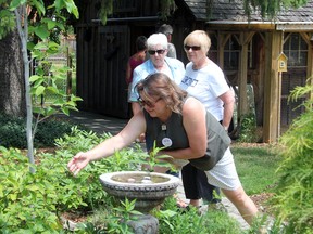 Joanna McEwen, in green, shows off some butterfly larvae in her large backyard garden on Maria Street. Her house was one of eight featured on this year's Communities in Bloom Garden Tour on Sunday, June 29. SHAUN BISSON/THE OBSERVER/QMI AGENCY  ​