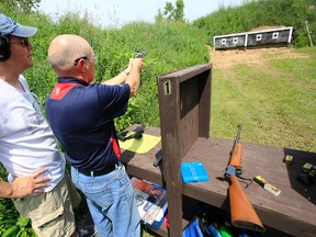 Shawn Bradley, left, of Belleville, Ont. and shooting instructor at Prince Edward Rod and Gun Club in the area of Lake on the Mountain, Ont., supervises a visitor at the pistol shooting range during the club's annual open house Saturday, June 28, 2014. - Jerome Lessard/The Intelligencer/QMI Agency