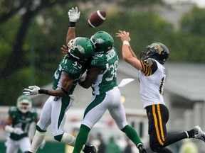 Roughriders defensive back Weldon Brown  (left) and teammate Tristan Jackson (38) try to block a pass intended for Tiger-Cats wide receiver Luke Tasker in Regina last night. (Reuters)