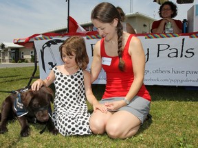 Harley, a Kingston 4 Paws Academy puppy in training, sits with six-year-old Isabelle Marois and her mother Meaghan Gauthier-Marois outside the Loyalist Emergency Services Amherstview Fire Hall on Saturday. Julia McKay/The Whig-Standard