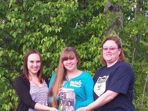 Kayla Stonehouse, left, and Loralee Stonehouse, right, present the money raised by participants and supporters of a recent slo-pitch tournament to Skyelur Smith, to help the teen’s family with medical expenses.