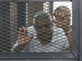 Mohamed Fahmy stands behind bars as he waits to listen the ruling at a court in Cairo June 23, 2014. REUTERS/ASMAA WAGUIH