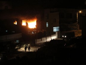 Israeli soldiers walk as flames are seen at the family home of an alleged abductor after a blast on the top floor in the West Bank City.

REUTERS/Ammar Awad