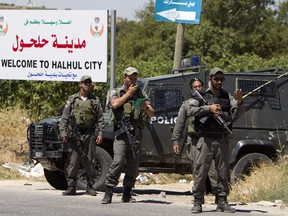 Israeli border policemen stand guard near their vehicle on July 1, 2014 at the entrance of the village of Halhul, in the West Bank, where the bodies of three missing Israeli teenagers were found. AFP PHOTO/ AHMAD GHARABLI