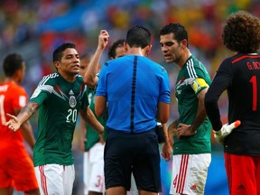 Mexico's players discuss with referee Pedro Proenca of Portugal after he called a penalty in favour of the Netherlands during their 2014 World Cup round of 16 game at the Castelao arena in Fortaleza June 29, 2014. (REUTERS/Eddie Keogh)