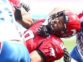 Stampeders runningback Jon Cornish takes a nasty hit from Alouettes defender Kyries Hebert during CFL action in Calgary on Saturday, June 28, 2014. (Darren Makowichuk/QMI Agency)