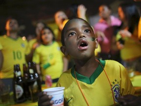 A Brazilian boy watches the 2014 World Cup Group A soccer match between Brazil and Cameroon being played in Brasilia, at the Corrilhos favela, near the World Cup stadium in Sao Paulo, June 23, 2014. (REUTERS/Nacho Doce)