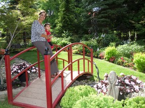 Bhama Rajgopal?s backyard garden features two wooden bridges, which span a dry creekbed. Rajgopal stands on one of the bridges with her three-year-old grandson, Tyson. (DEREK RUTTAN/ The London Free Press)