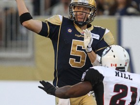 Winnipeg Blue Bombers QB Drew Willy throws a pass under pressure from Ottawa RedBlacks LB T.J. Hill during CFL action at Investors Group Field in Winnipeg, Man., on Thu., July 3, 2014. Kevin King/Winnipeg Sun/QMI Agency